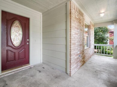 Entrance to property with a porch and brick siding