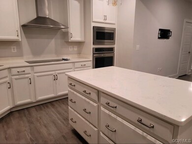 Kitchen with white cabinets, dark hardwood / wood-style flooring, and appliances with stainless steel finishes