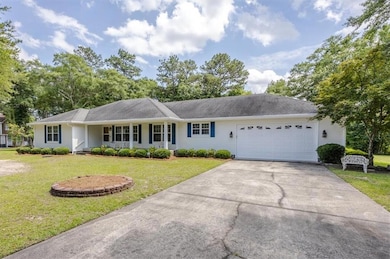 Ranch-style home featuring a garage, concrete driveway, and a front lawn
