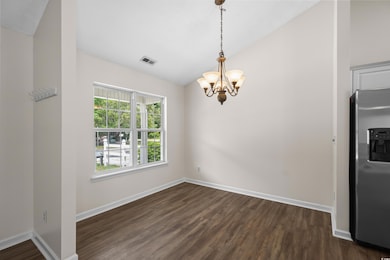 Unfurnished dining area featuring lofted ceiling, a chandelier, dark wood finished floors, and baseboards