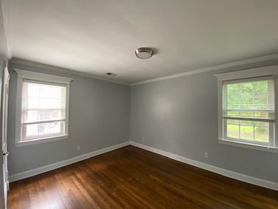 Empty room featuring dark wood-type flooring and ornamental molding