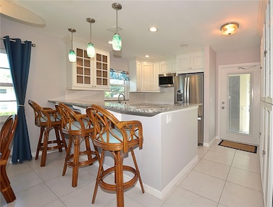 Kitchen featuring recessed lighting, a peninsula, decorative backsplash, glass insert cabinets, and stainless steel appliances