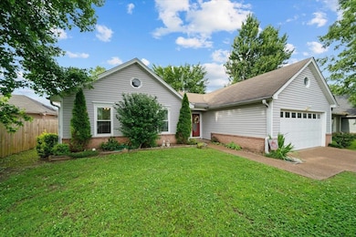 Single story home with brick siding, a garage, and driveway