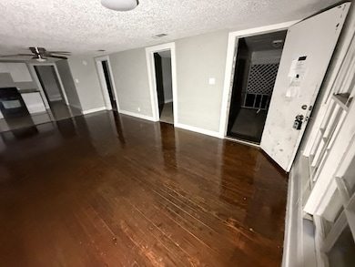 Unfurnished living room with a textured ceiling and dark wood-type flooring