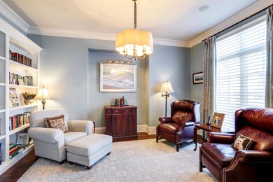 This versatile room features a wall of custom-built bookshelves, a sweet architectural niche to display a treasured piece of art, hardwood floors and crown molding.