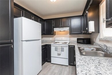 Kitchen featuring light countertops, white appliances, under cabinet range hood, a sink, and light wood-style floors