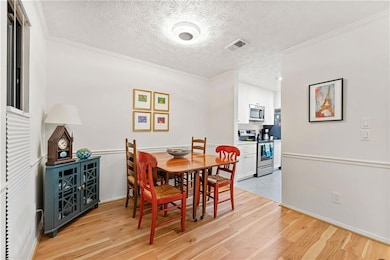 Dining room featuring light wood-style flooring, ornamental molding, and a textured ceiling