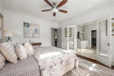 Bedroom with wood finished floors, ornamental molding, ceiling fan, and french doors