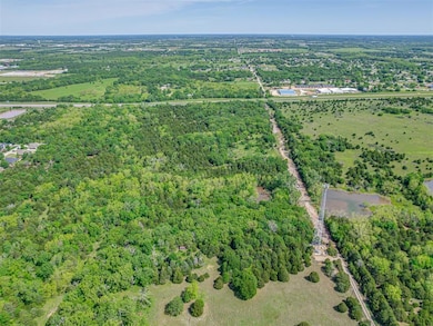 Aerial view of property and surrounding area with a heavily wooded area and a nearby body of water