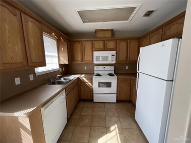 Kitchen featuring sink, white appliances, and light tile patterned flooring