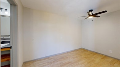 Empty room with baseboards, a ceiling fan, and light wood-style floors