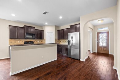 Kitchen with dark wood-type flooring, black applia