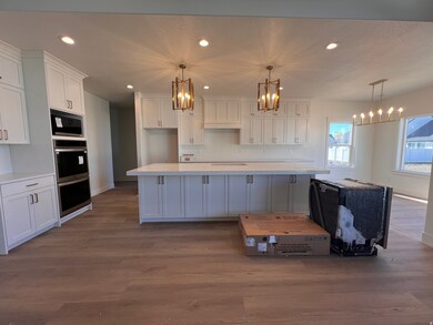 Kitchen featuring white cabinets, recessed lighting, dark wood-style flooring, decorative light fixtures, and stainless steel double oven