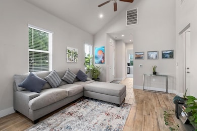 Living area featuring ceiling fan, high vaulted c