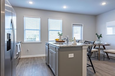 Kitchen featuring a center island with sink, appliances with stainless steel finishes, hardwood / wood-style flooring, and a healthy amount of sunlight