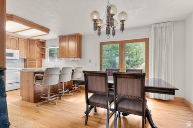 Dining room with a textured ceiling, light wood-type flooring, and a chandelier