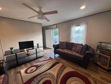 Living room featuring wood finished floors, ceiling fan, a textured ceiling, ornamental molding, and recessed lighting