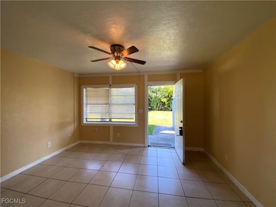 Empty room with a textured ceiling, light tile patterned flooring, and a ceiling fan