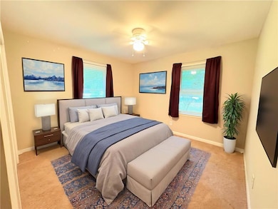 Bedroom featuring light colored carpet, multiple windows, and baseboards