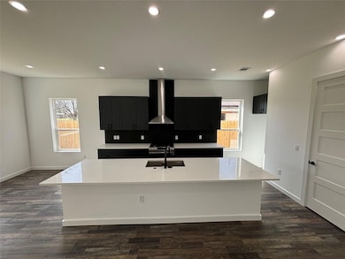 Kitchen featuring wall chimney exhaust hood, dark