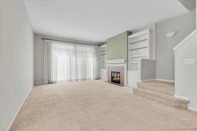 Unfurnished living room featuring light carpet, a tile fireplace, built in shelves, and stairs