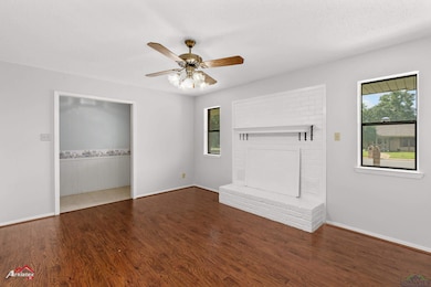 Unfurnished living room with plenty of natural light, wood finished floors, ceiling fan, and a fireplace