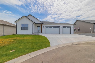 View of front of property featuring an attached garage, concrete driveway, board and batten siding, and a front yard