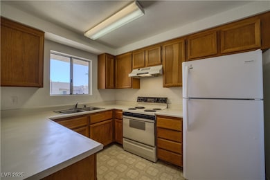 Kitchen featuring white appliances, light countertops, and brown cabinets