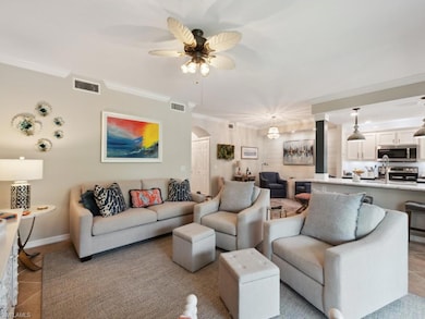 Living area with arched walkways, light tile patterned flooring, crown molding, and a ceiling fan