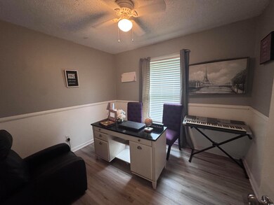 Office space with wood finished floors, a textured ceiling, ceiling fan, and baseboards