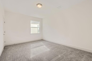 Empty room with light colored carpet and baseboar