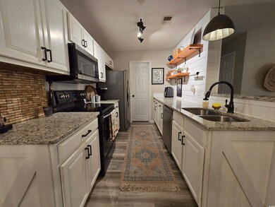 Kitchen featuring stainless steel appliances, a sink, open shelves, decorative backsplash, and white cabinets