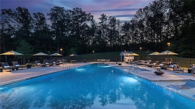 Pool at dusk with a community pool, fence, and a p