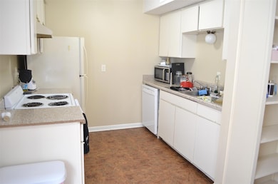 Kitchen with white appliances, white cabinets, un