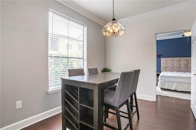 Dining room featuring a chandelier, crown molding, and dark wood finished floors