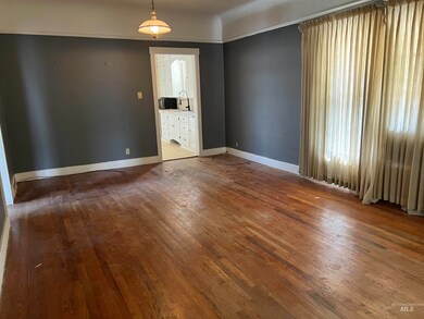 Spare room featuring dark wood-style flooring and baseboards