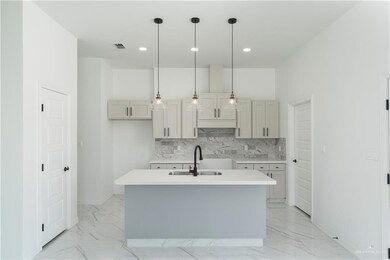 Kitchen featuring sink, light tile patterned flooring, decorative backsplash, and an island with sink