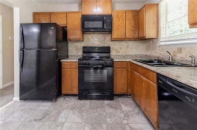 Kitchen with black appliances, a sink, light count