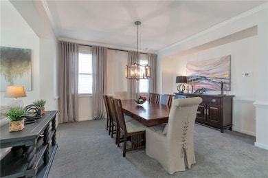 Dining room featuring light carpet, crown molding, and a chandelier