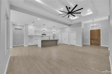 Unfurnished living room with ceiling fan with notable chandelier, light hardwood / wood-style floors, beamed ceiling, and sink