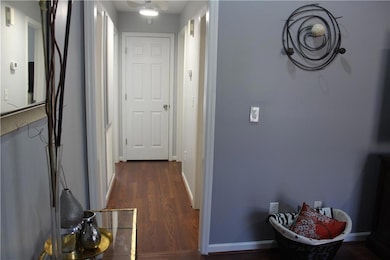 Corridor with dark wood-type flooring and baseboards