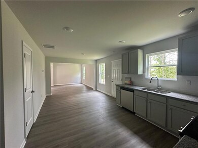 Kitchen with stainless steel dishwasher, gray cabinetry, dark wood finished floors, and recessed lighting