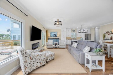 Living room featuring an inviting chandelier, ornamental molding, light wood-type flooring, and a healthy amount of sunlight