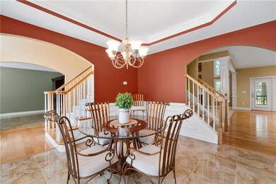 Dining area featuring arched walkways, split staircase, a chandelier, and crown molding