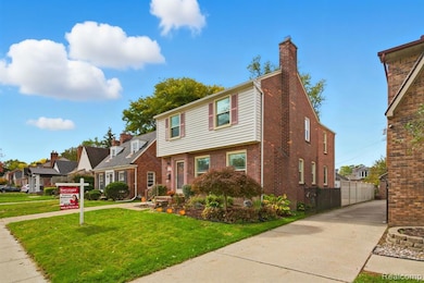 Colonial house featuring a front yard, brick siding, a residential view, and a chimney