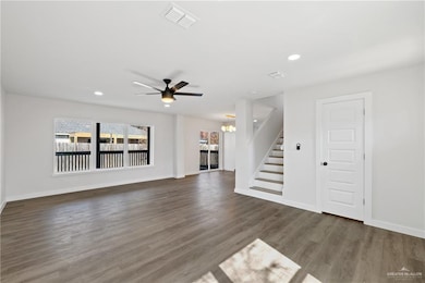 Unfurnished living room with dark hardwood / wood-style floors and ceiling fan with notable chandelier