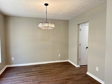 Unfurnished room featuring baseboards, dark wood-s
