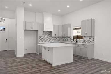Kitchen featuring recessed lighting, a kitchen island, dark wood-type flooring, tasteful backsplash, and gray cabinetry