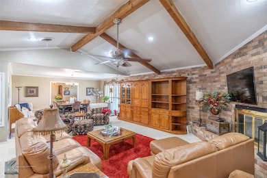Carpeted living room featuring a chandelier, a ceiling fan, brick wall, and a fireplace