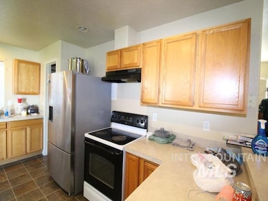 Kitchen with white electric range, light countertops, under cabinet range hood, and stainless steel refrigerator with ice dispenser